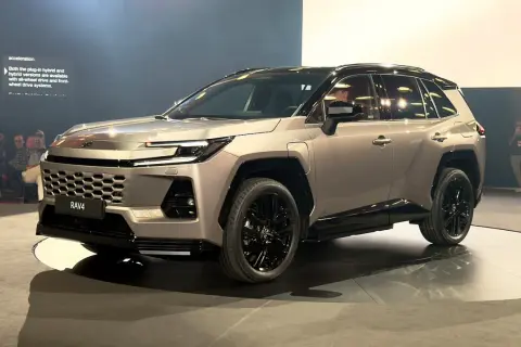 Nowy Toyota RAV4 2026 w kolorze szampańskim, z czarnymi felgami i przyciemnianymi szybami, prezentowany na scenie.