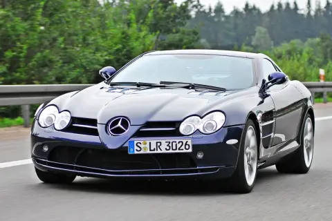 Granatowy SLR McLaren pędzi po autostradzie, otoczony zielenią.