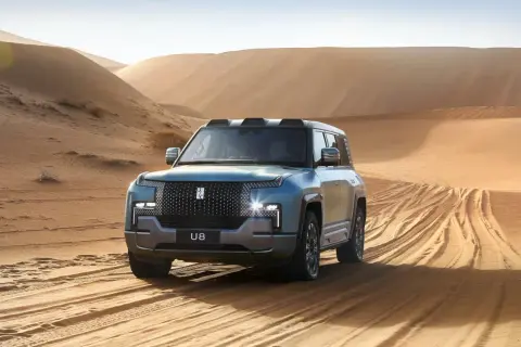 Niebieski SUV U8 przemierza piaszczyste wydmy, zostawiając ślady opon na pustyni.