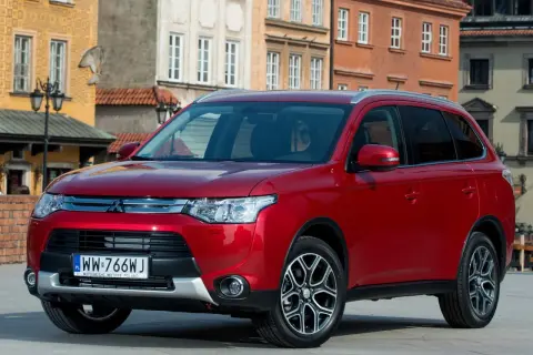 Czerwony Mitsubishi Outlander na tle kamienic. Wiele osób szuka mitsubishi outlander opinie przed zakupem.