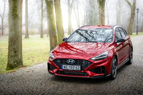 Czerwony Hyundai i30 Wagon N Line na kamienistej drodze w mglistym parku.