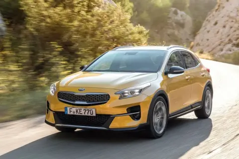 Żółty Kia XCeed na krętej drodze. Wiele osób szuka kia xceed opinie, ten model wygląda obiecująco.