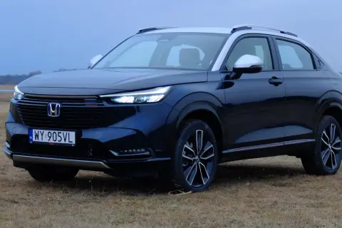 Ciemnoniebieski Honda HR-V na tle suchej trawy i jeziora.