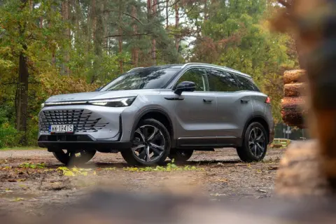 Srebrny SUV na leśnej drodze. Wiele osób szuka baic 7 opinii przed zakupem.