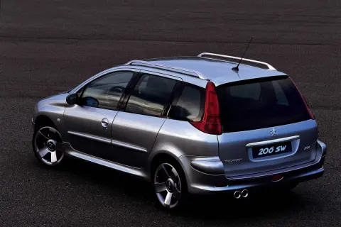 Srebrny Peugeot 206 SW z relingami dachowymi i podwójnym wydechem, zaparkowany na ciemnym asfalcie.