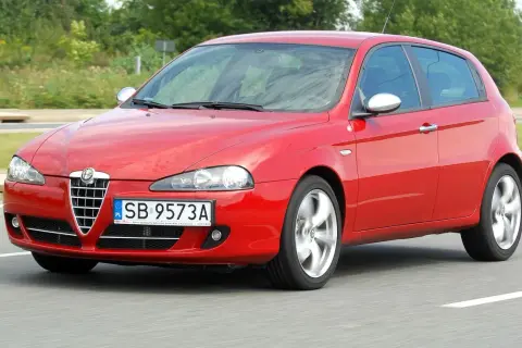 Czerwone Alfa Romeo 147 1.9 JTD w ruchu, z widocznymi felgami w ruchu.