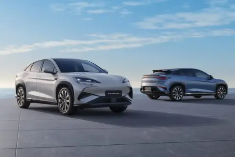 Dwa nowoczesne chińskie samochody elektryczne, BYD SEALION 7, stoją na tle błękitnego nieba i morza.