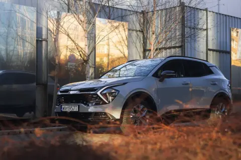 Nowy kia crossover odbija się w lustrzanych panelach, tworząc surrealistyczny krajobraz miejski.