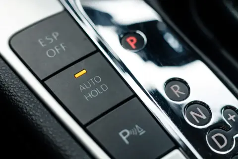 Przyciski ESP OFF, AUTO HOLD i P w samochodzie. Dźwignia zmiany biegów z literami P, R, N, D i przyciskiem "+", sugerująca tryb tiptronic.