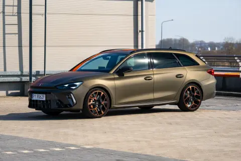 Złoty Cupra Leon Kombi z miedzianymi akcentami na felgach i dachu, zaparkowany na zewnątrz.