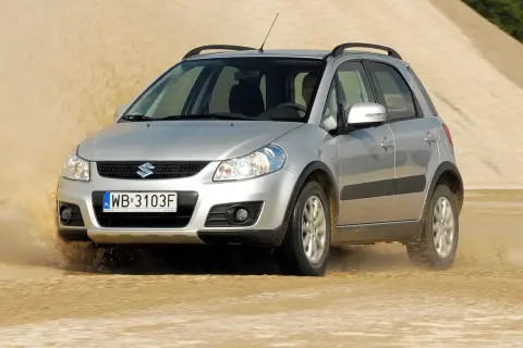 Srebrny Suzuki SX4 1.6 benzyna pokonuje piaszczystą wydmę, wzbijając tumany kurzu.
