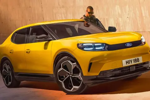 Nowy Ford Capri 2025 w jaskrawym żółtym kolorze, z nowoczesnymi światłami LED i stylowymi felgami. Mężczyzna w okularach wychodzi z samochodu.