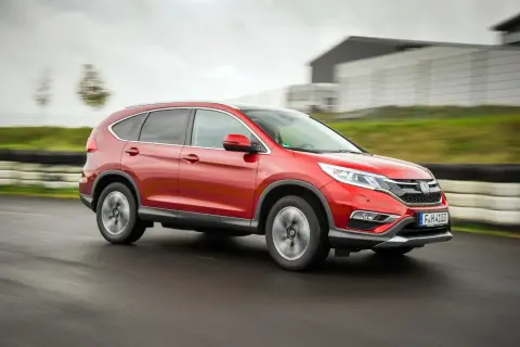 Czerwony Honda CR-V 4. generacji pędzi po torze wyścigowym, ukazując swoją dynamiczną sylwetkę.