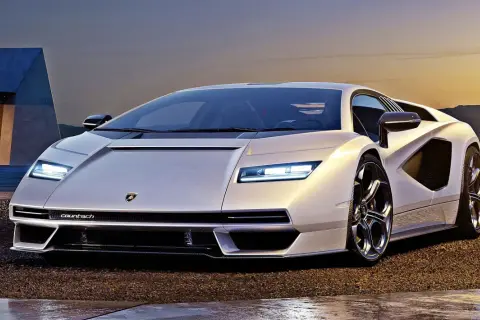 Biały Lamborghini Countach L, ikona motoryzacji, prezentuje swoje ostre linie na tle zachodzącego słońca.