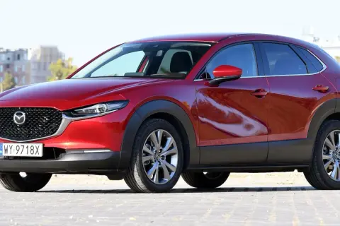 Czerwona Mazda CX-30 z polskimi tablicami rejestracyjnymi stoi na zewnątrz.