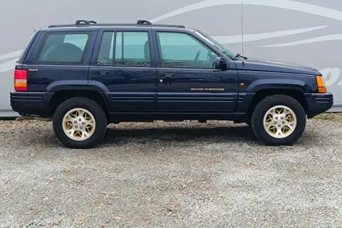 Granatowy Jeep Grand Cherokee ZJ z lat 90. na złotych felgach, gotowy na przygodę.