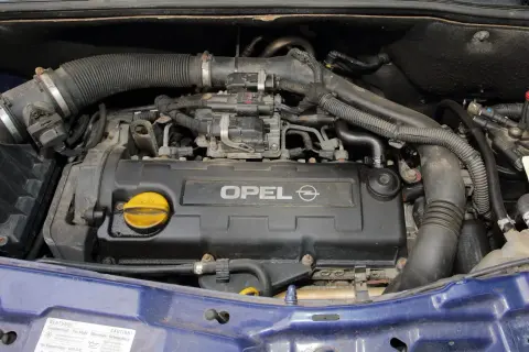 Silnik Opla Meriva A z widocznym napisem OPEL. Widać przewody, rury i żółty korek wlewu oleju.