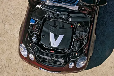 Silnik V6 om642 Mercedesa E-klasy, z otwartą maską, na tle spękanej ziemi.