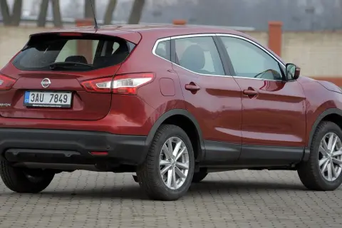 Czerwony Nissan Qashqai 1.6 benzyna z czeskimi tablicami rejestracyjnymi stoi na utwardzonym podjeździe.