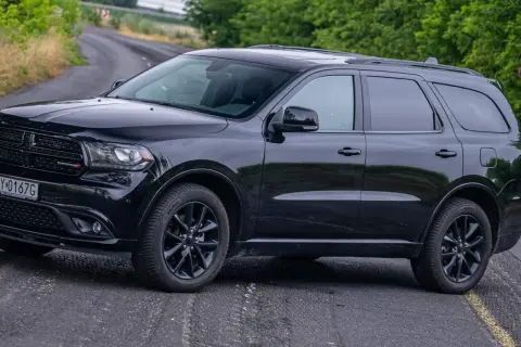 Czarny Dodge Durango 5.7 Hemi na krętej drodze, otoczony zielenią. Potężny SUV gotowy na każdą przygodę.