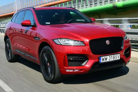 Czerwony Jaguar F-Pace na drodze. Kierowca w środku. Wiele pozytywnych jaguar f pace opinie potwierdza jego styl.