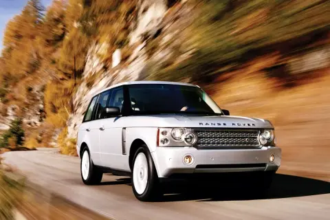 Biały Range Rover L322 pędzi po krętej drodze wśród jesiennych drzew.