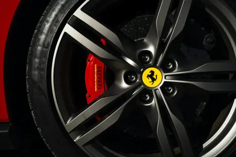 Felga z logo Ferrari, czerwony zacisk hamulcowy Brembo i opona Pirelli. Marka samochodu na i.
