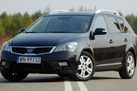 Czarny Kia Ceed 1. kombi na drodze, z kierowcą za kierownicą.