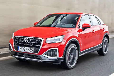 Czerwone Audi Q2 pędzi po drodze, błyszcząc w słońcu.