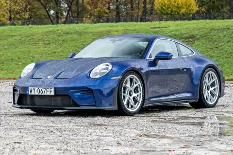 Niebieskie Porsche 911 na mokrej nawierzchni, z kroplami deszczu na karoserii. Czy to najtańsze porsche, jakie można znaleźć?