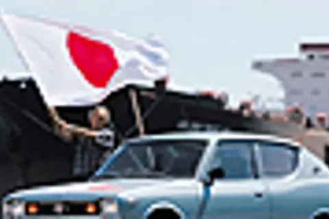 Jasnoniebieski Datsun 100A z flagą Japonii na tle statku.