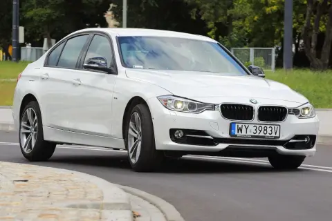 Białe BMW 318i z polskimi tablicami rejestracyjnymi WY 3983V jedzie po drodze.