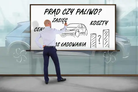 Mężczyzna pisze na tablicy "Prąd czy paliwo?", rysuje samochód i wykresy, zastanawiając się, ile kosztuje samochód elektryczny.