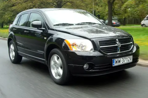 Czarny Dodge Caliber w ruchu, z mokrą karoserią. Wiele osób szuka dodge caliber opinie, by dowiedzieć się więcej o tym modelu.
