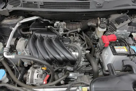 Silnik Nissan Qashqai J10, z widocznym kolektorem dolotowym, akumulatorem i alternatorem.