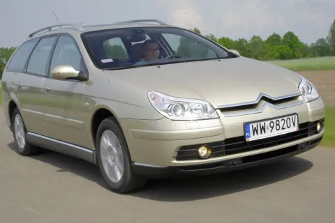 Złoty Citroen C5 kombi w ruchu drogowym. Kierowca za kierownicą. Wiele pozytywnych citroen c5 opinie potwierdza jego komfort.