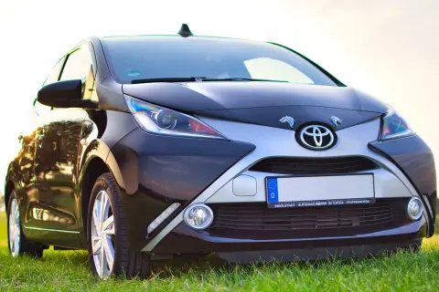 Czarny Toyota Aygo, jeden z popularnych japońskich marek aut, na tle zielonej trawy.