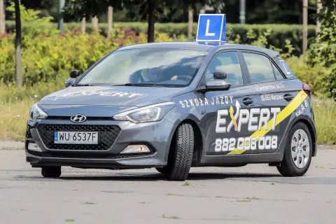 Szara Skoda z literą L na dachu, oznakowana jako "Szkoła Jazdy EXPERT". Pytanie o prawo jazdy od ilu lat jest tu na miejscu, bo to auto do nauki jazdy.