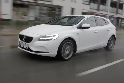 Białe Volvo V40 D3 w ruchu miejskim, na mokrej nawierzchni.