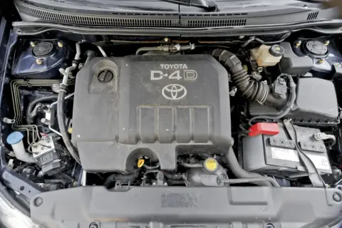 Silnik D-4D w Toyocie Corolla E12. Widoczny jest plastikowy kolektor dolotowy, akumulator i inne elementy komory silnika.