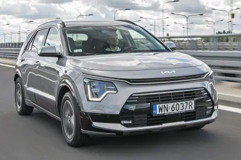 Szary Kia Niro w ruchu drogowym. Sprawdź atrakcyjną kia niro cena i wybierz swój nowy samochód.