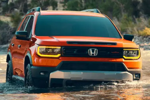 Pomarańczowy Honda Passport TrailSport pokonuje wodę, gotowy na przygodę.
