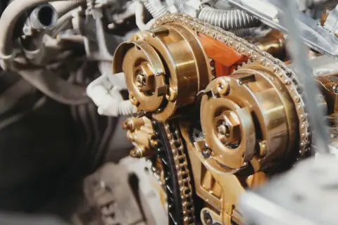 Zbliżenie na mechanizm rozrządu silnika diesla z widocznym łańcuchem i kołami zębatymi.