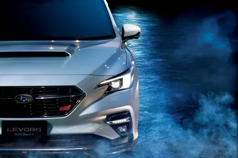 Srebrny Subaru Levorg STI Sport z włączonymi światłami, otoczony niebieską mgłą, gotowy do jazdy.