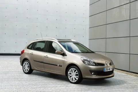 Beżowe Renault Clio 3 1.2 benzyna na tle nowoczesnej architektury.
