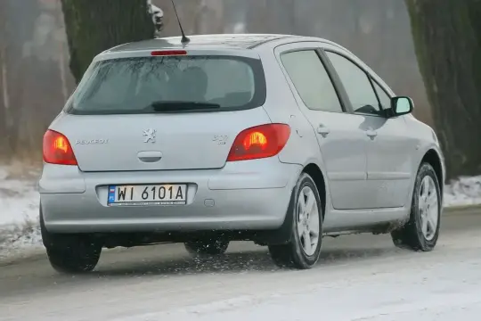 Srebrny Peugeot 307 2.0 HDI na śliskiej, zimowej drodze.