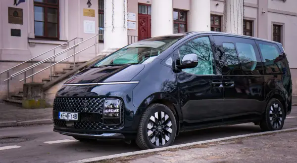 Czarny Hyundai Staria, nowoczesny van, zaparkowany przed budynkiem z kolumnami i schodami.