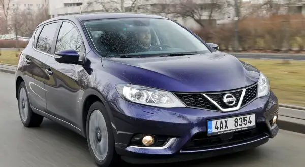 Fioletowy Nissan Pulsar w ruchu ulicznym. Wiele osób szuka nissan pulsar opinie przed zakupem.