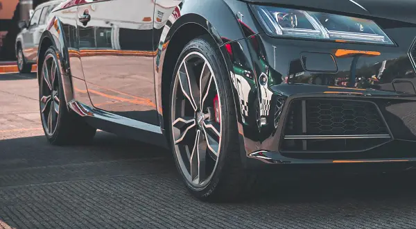 Błyszczące, czarne auto sportowe z felgami i widocznym rantem ochronnym opony.