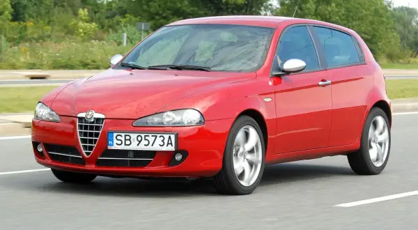 Czerwone Alfa Romeo 147 1.9 JTD w ruchu, z widocznymi felgami w ruchu.